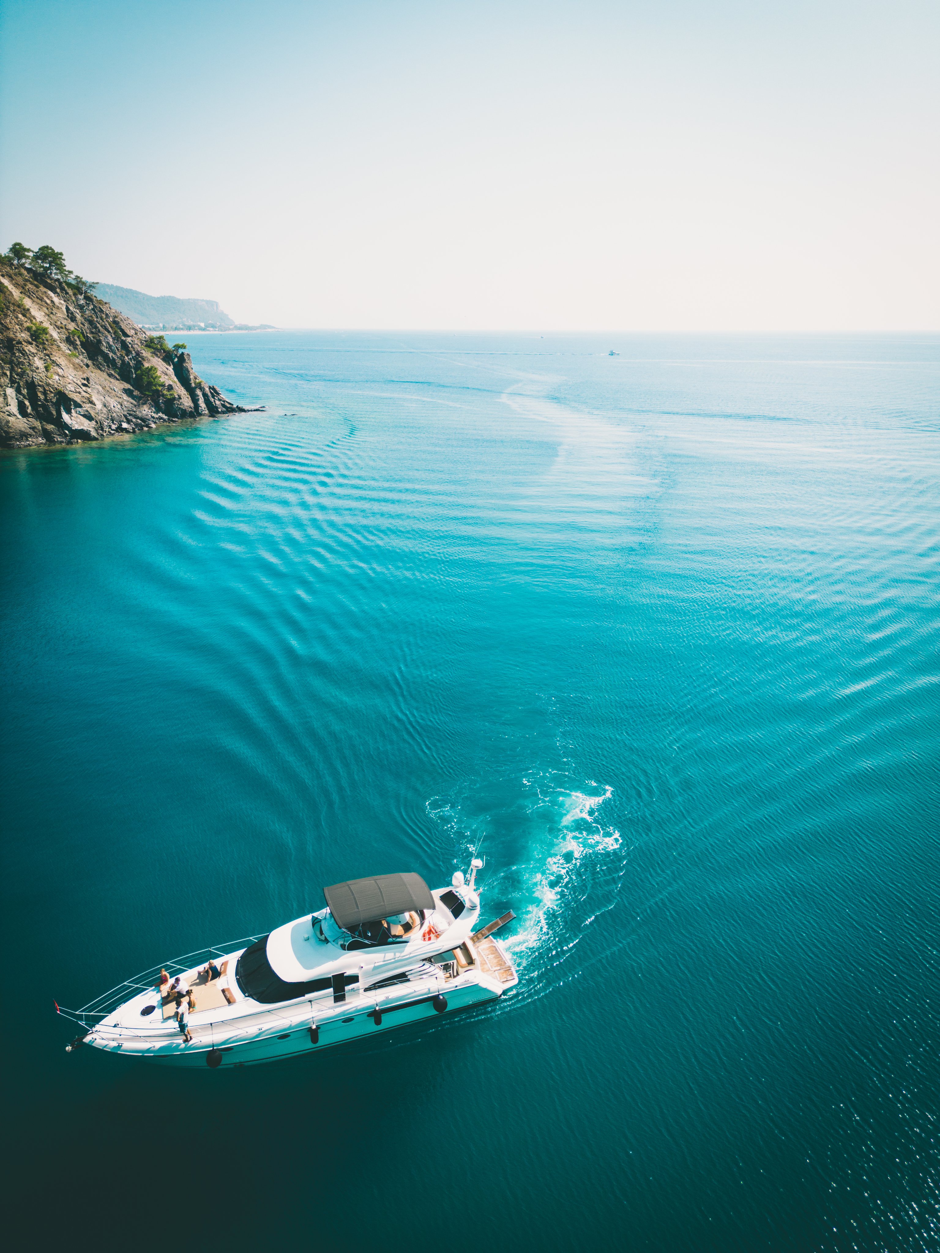 Luxury motor yacht cruising through clear turquoise coastal waters